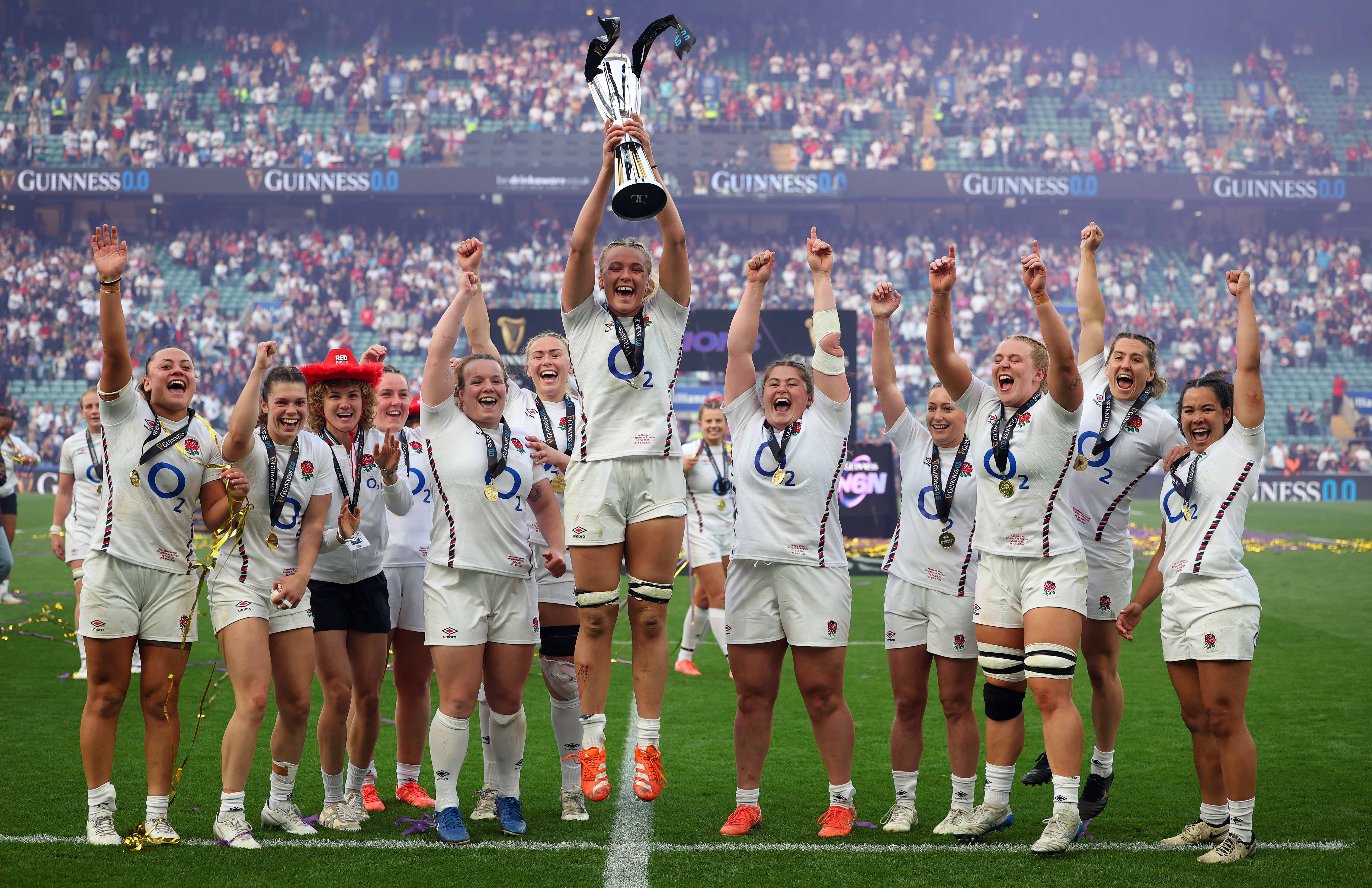 England's women's rugby team celebrating a victory, holding the trophy.