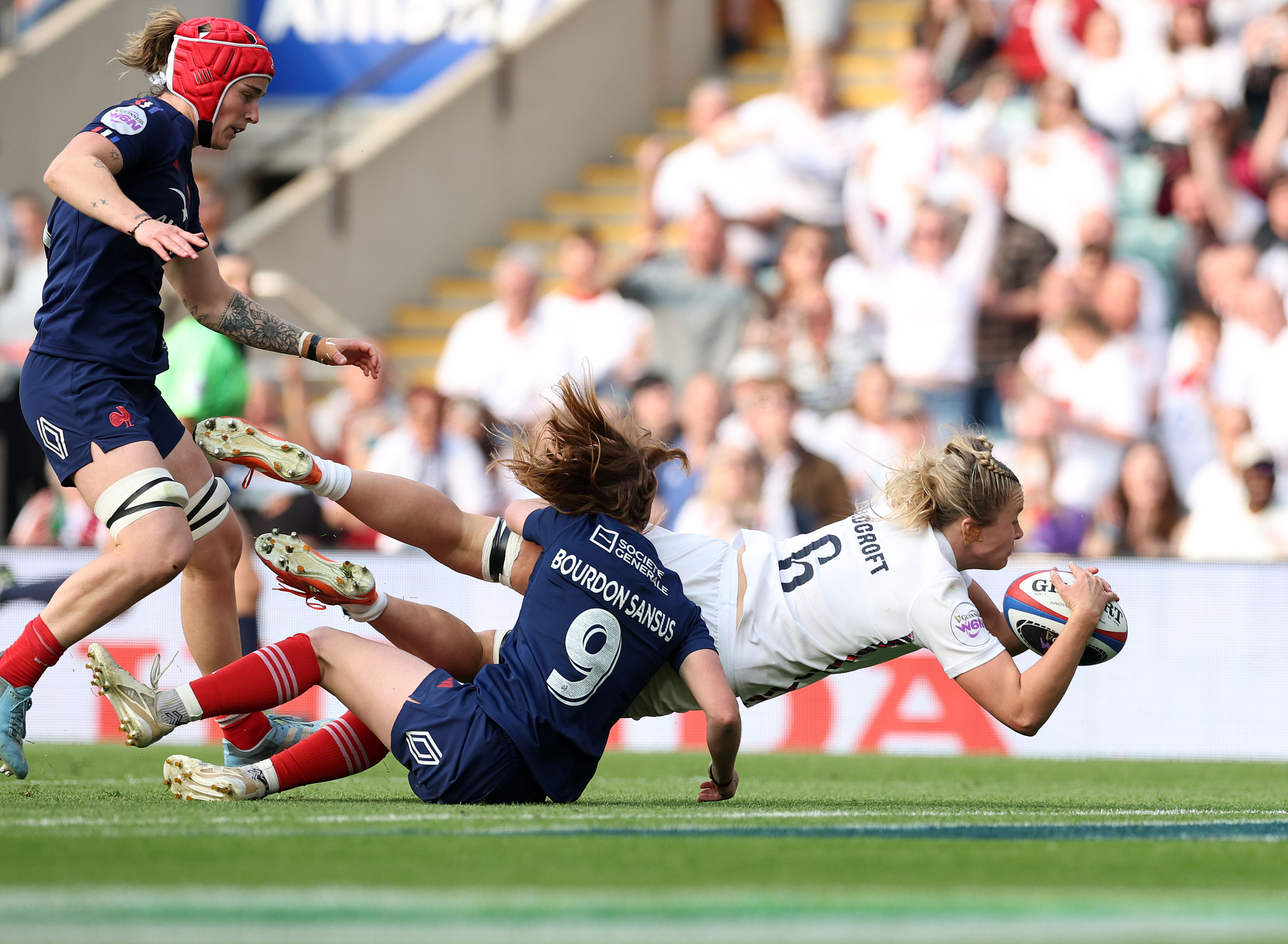 Photograph of a rugby match between England and France, showing players tackling for the ball.