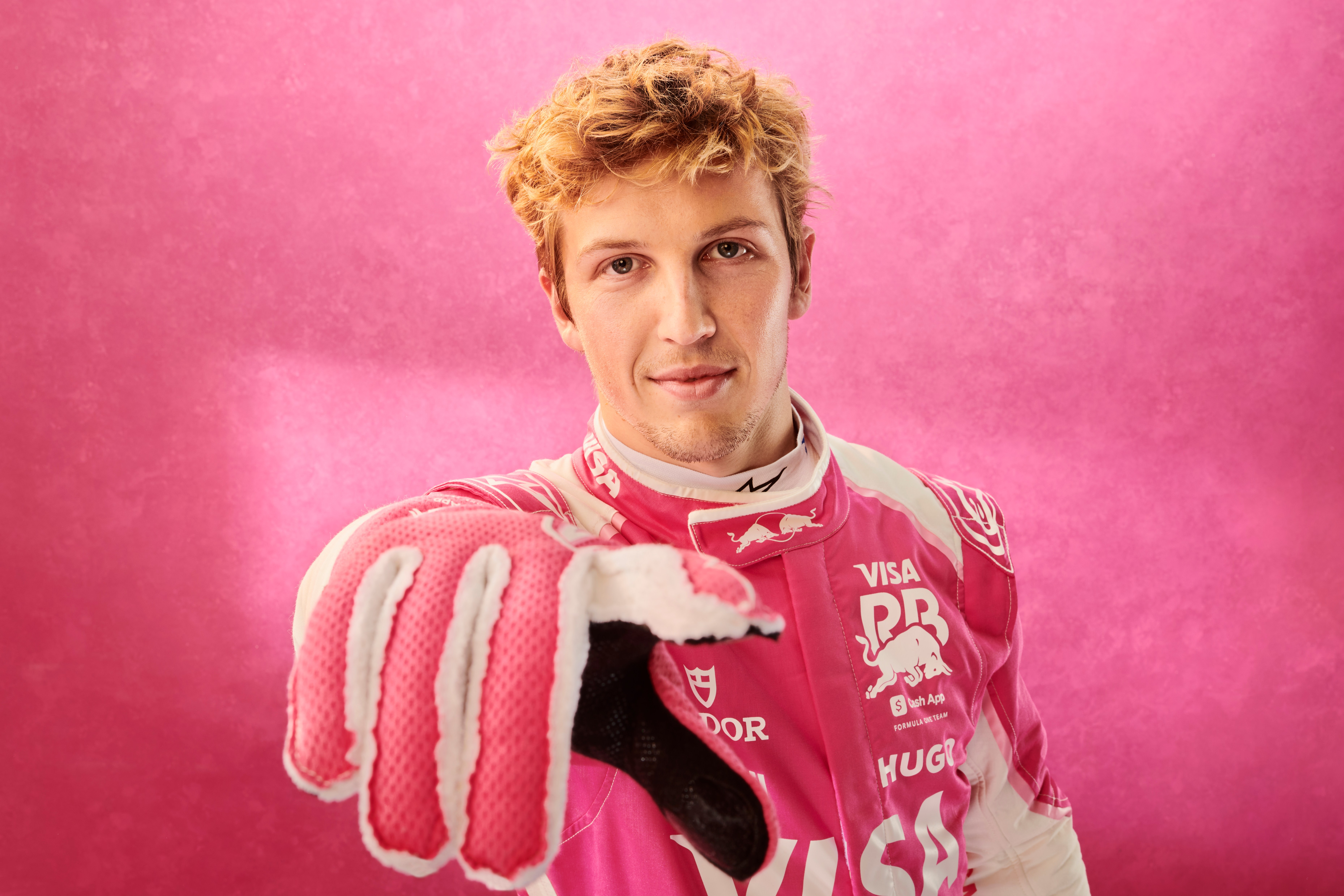 Liam Lawson in pink racing suit and gloves.