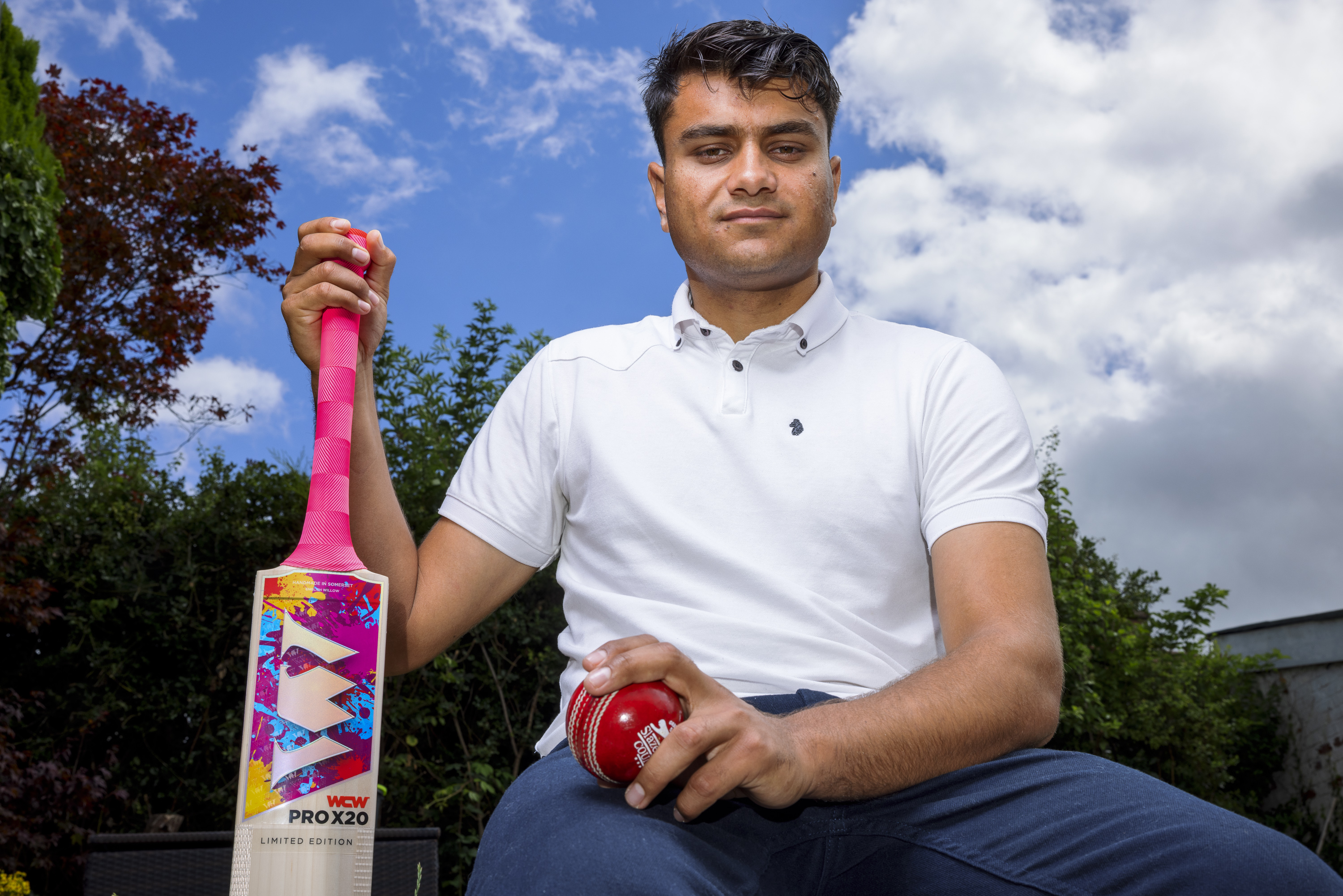 Adnan Miakhel, holding a cricket bat and ball during his journey in the UK.