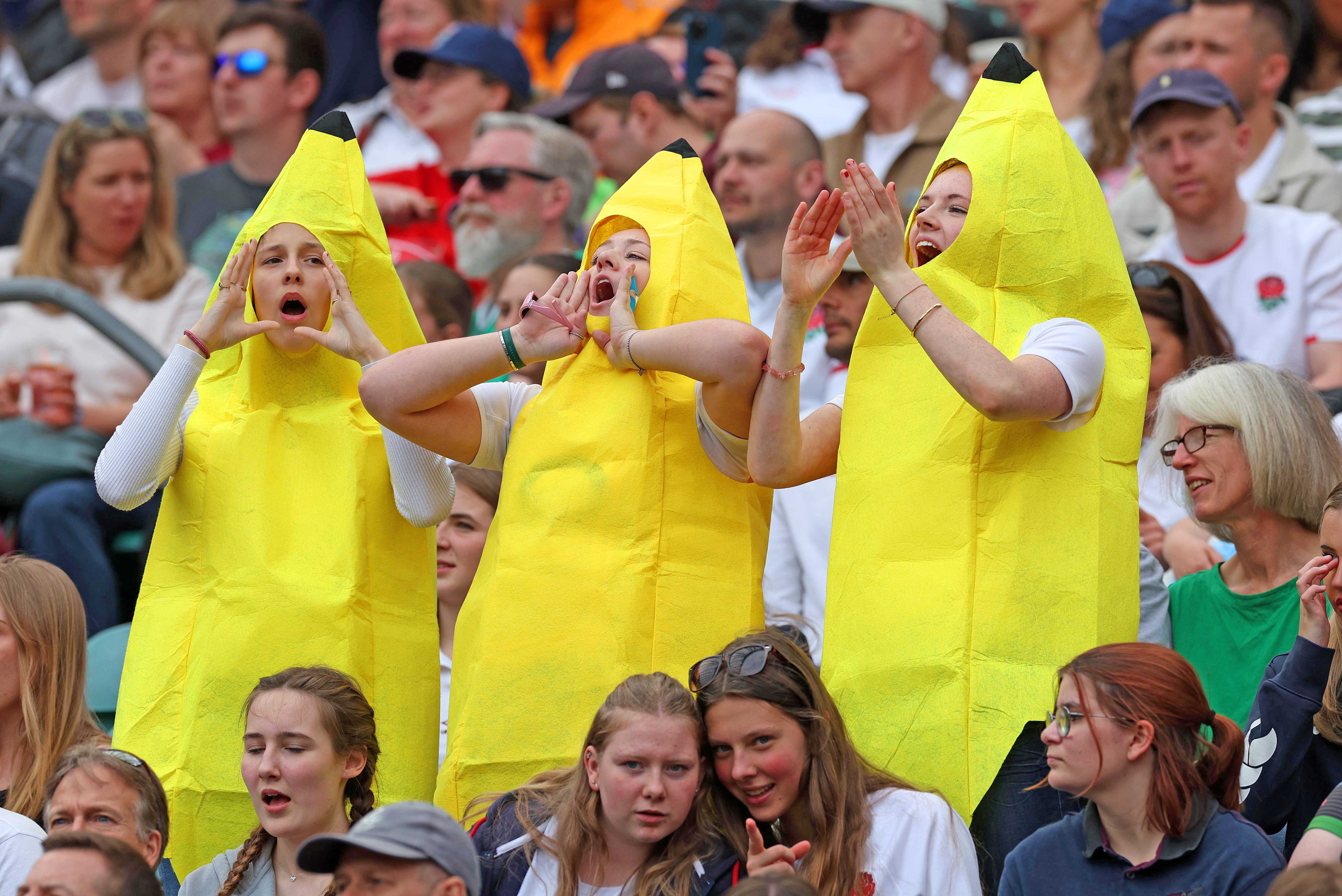 Three women in banana costumes cheering at a sporting event.